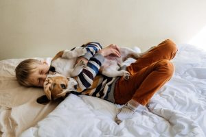 Child on bed hugging a dog laying down