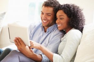 couple on couch looking at a tablet together